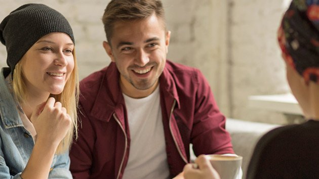 Junge Leute sitzen beisammen und lachen.