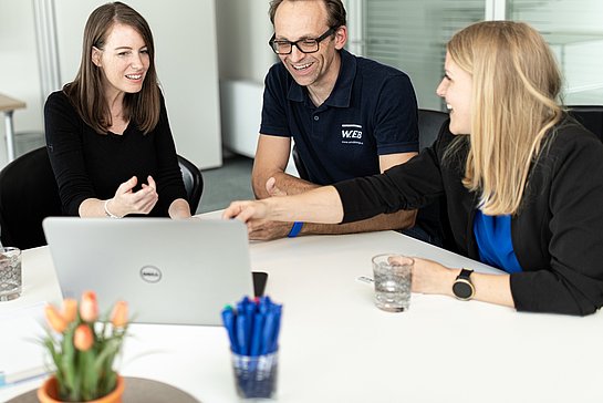 Mitarbeiter:innen der WEB Windenergie diskutieren am Tisch sitzend