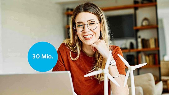 Junge Dame vor dem Laptop mit kleinen Windrädern, die auf dem Schreibtisch stehen